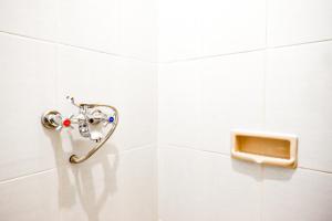 a white tiled bathroom with a hand rail at RedDoorz @ Jalan Wonosari KM.9 in Yogyakarta