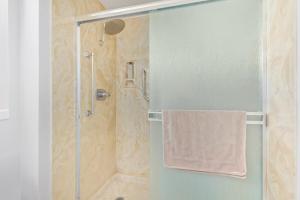 a bathroom with a shower with a towel on a glass door at Naturally Modest & Quiet in Sun City West +13 photos