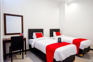 two beds in a room with a mirror and a chair at RedDoorz @ Jalan Wonosari KM.9 in Yogyakarta
