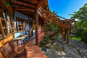 a patio of a house with a table and benches at Pousada Villa Da Prainha in Ilhabela