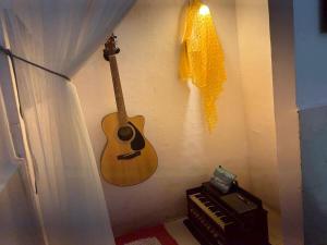 a guitar hanging on a wall next to a piano at Sun Bloom in Mumbai