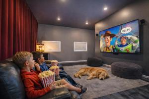 two boys and a dog sitting on a couch watching tv at Recharge by The River by NW Comfy Cabins in Leavenworth
