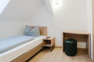 a small bedroom with a bed and a table at Cityhotel Donauwörth in Donauwörth