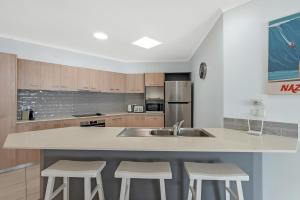 a kitchen with a sink and two stools at Relax at Trinity in Trinity Beach