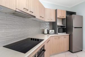 a kitchen with wooden cabinets and a stainless steel refrigerator at Relax at Trinity in Trinity Beach