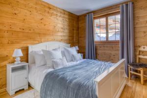 a bedroom with a white bed and a wooden wall at Ski-in Ski-out with Chimney and view in Les Crosets