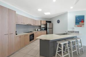 a kitchen with wooden cabinets and a counter with bar stools at Relax at Trinity in Trinity Beach