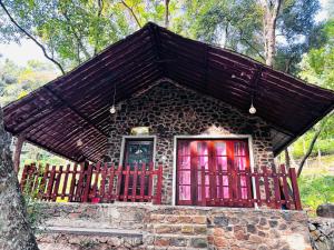 a small stone house with red doors and a fence at Sandungira Eco Resort in Belihuloya