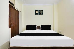 a bedroom with a large white bed with black pillows at Hotel O Dwarka Metro in New Delhi