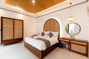 a bedroom with a bed and a desk and a mirror at Green Mutiara Jimbaran in Jimbaran