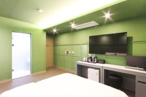 a room with green walls and a bed and a tv at Novahotel in Samgong