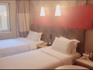 a hotel room with two beds and a window at Ibis Tianjin Development Zone TEDA Third Avenue in Binhai