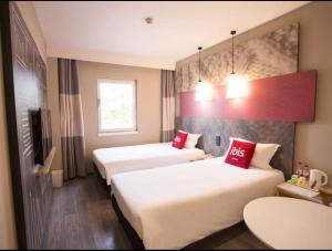 a hotel room with two beds with red pillows at Ibis Tianjin Development Zone TEDA Third Avenue in Binhai