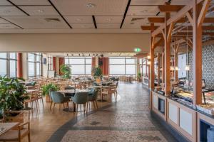a restaurant with tables and chairs and windows at IFA Schöneck Hotel & Ferienpark in Schöneck