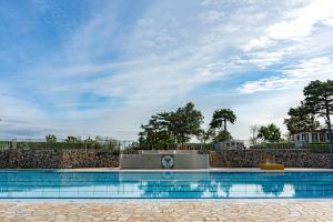 a large swimming pool with a stone wall and a sky at Glamping Sistiani in Lido di Spina