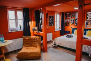 a bedroom with orange walls and a bed and a couch at sleepArt music in Celle