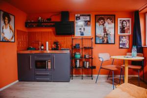 a kitchen with an orange wall with a stove and a table at sleepArt music in Celle