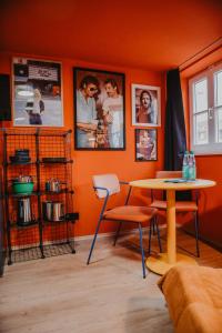a room with an orange wall with a table and chairs at sleepArt music in Celle