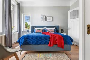 a bedroom with a blue bed with a red blanket at Villa Hygge Kappeln - Design Ferienwohnungen in Kappeln