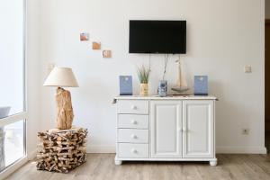 a white dresser with a tv on a wall at Ferienwohnung Bootsteg Moba-Travel in Priwall