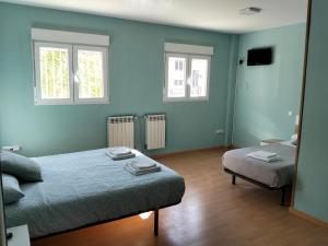 a bedroom with two beds and two windows at Hostal Camino micológico in Navaleno +18 photos