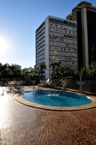 a swimming pool with a fountain and a building at Jandaia Hotel Campo Grande in Campo Grande
