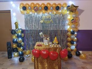a gold and black balloon arch with a table with balloons at Ooty Gate Residency in Ooty