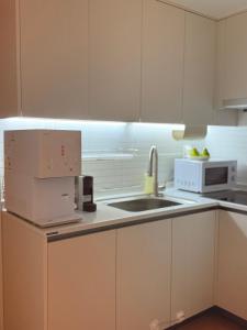 a white kitchen with a sink and a microwave at stable home#신축#천호역2분#KSPO#롯데월드#롯데타워#아산병원#코엑스#가족여행#장박할인 in Seoul