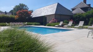 a swimming pool with lounge chairs and a house at La Charmeraie d'Aumâtre in Aumâtre