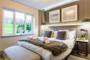 a bedroom with a bed with a blanket and two windows at Arran Shores Luxury Shorefront Garden Terrace Apartment 6 in Lamlash