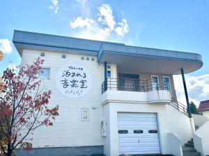 a white building with a clock on the side of it at 泊まれる音楽室 The Music Room-inn in Naie