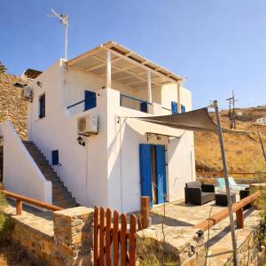 a white house with a blue door and a fence at Blue Calm House Kythnos in Agios Dimitrios