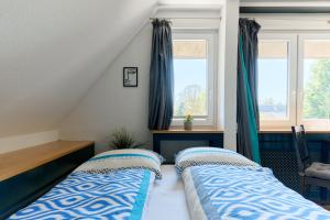 a bedroom with two beds and two windows at Ferienwohnung Ostseeperle Moba-Travel in Travemünde