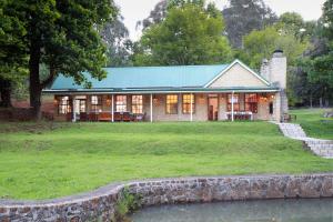 a house with a green roof on a grass field at New England Cottage by First Private Stays in Underberg