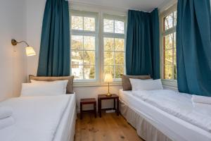 two beds in a room with blue curtains at Mariene Home Apartments - Am Hammer in Rösrath