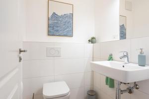 a white bathroom with a sink and a toilet at Mariene Home Apartments - Am Hammer in Rösrath +24 photos
