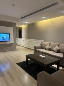 a living room with a couch and a tv at Hayat Watheer for serviced Apartment in Dammam