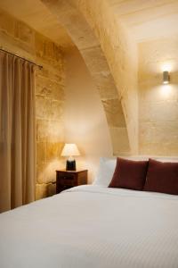 a bedroom with a bed and a table with a lamp at Nelsonhaus -Boutique Guesthouse in Cospicua