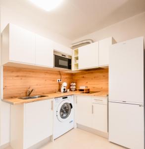 a kitchen with white cabinets and a washer and dryer at Oasis in Costa Calma