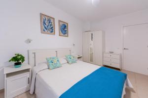 a white bedroom with a bed with blue pillows at Oasis in Costa Calma +10 photos