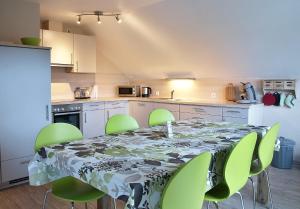 a kitchen with a table and green chairs around it at Ferienwohnung Storchenblick in Herbolzheim