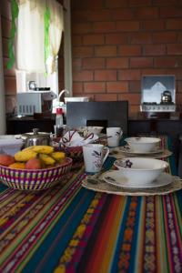a table with bowls of fruit and plates on it at Hostal Cattleya in Puerto Baquerizo Moreno