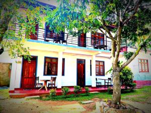 a white building with red doors and a tree at Parakum Rest Rooms in Polonnaruwa +29 photos