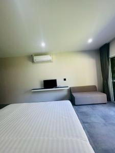 a bedroom with a white bed and a couch at Blue Mountain Kamala Phuket in Kamala Beach