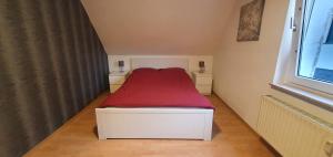 a small bedroom with a red bed and a window at Wohnung direkt an den Externsteinen in Horn-Bad Meinberg