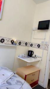 a room with a desk and a shelf with a tv at Fern Villa Hotel - Albert Road in Blackpool