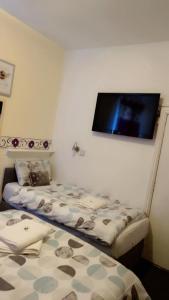 two beds in a room with a tv on the wall at Fern Villa Hotel - Albert Road in Blackpool