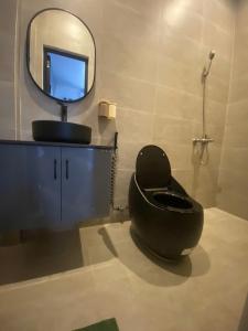a bathroom with a black toilet and a mirror at NEMO house in Cu Lao Thu