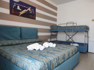 a bedroom with a bed with towels and bunk beds at Hotel Rodi Beach FRONTE SPIAGGIA in Rodi Garganico