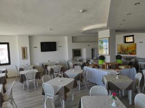 a restaurant with tables and chairs and a flat screen tv at Hotel Rodi Beach FRONTE SPIAGGIA in Rodi Garganico